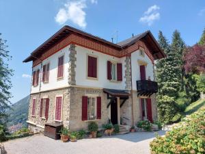 una gran casa con persianas rojas en una colina en Villa Annamaria - b&b en Ballabio
