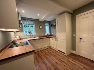 a kitchen with white cabinets and a sink and a window at Quaint self contained cottage near Edinburgh. in Loanhead