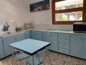 eine Küche mit blauen Schränken, einem Tisch und einem Fenster in der Unterkunft Finca Tylia, Olta, Calpe in Benissa