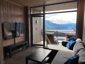 een woonkamer met een bank en een groot raam bij New apartment, Gausta in Rjukan. Ski in/ ski out in Rjukan