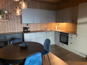 una cocina con mesa y sillas y una cocina con armarios blancos. en New apartment, Gausta in Rjukan. Ski in/ ski out en Rjukan