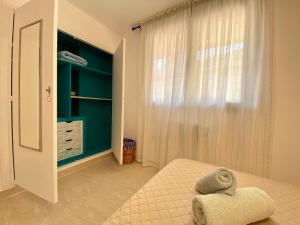 um quarto com uma cama e uma janela com uma cadeira em AZAFRAN apartamento para descanso cerca de la playa em Calpe