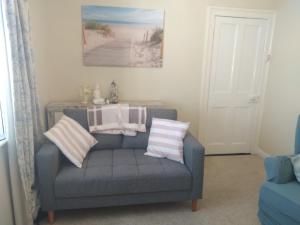 a living room with a blue couch with striped pillows at Sea View Cottage, 2 bedrooms with stunning views in Cobh