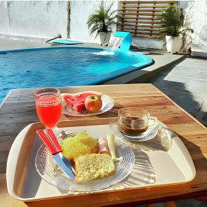 una bandeja de comida en una mesa junto a la piscina en Pousada Costa do Mar, en Luís Correia