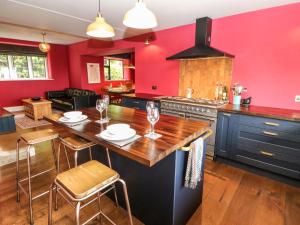 a kitchen with red walls and a wooden table and chairs at Warley Lodge in Halifax