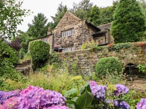 an old stone house with flowers in the foreground at Warley Lodge in Halifax