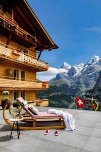 a bed on a balcony with a view of a mountain at Eiger Mürren Swiss Quality Hotel in Mürren