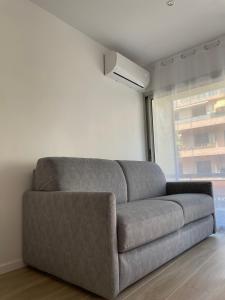 a gray couch in a living room with a window at Idéalement situé, vue mer & Parking privée gratuit in Canet-en-Roussillon