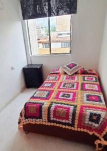 Un dormitorio con una cama con una manta de colores. en Hermoso apartamento, con todas las comodidades., en Medellín