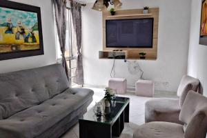 sala de estar con sofá y TV en Hermoso apartamento, con todas las comodidades. en Medellín