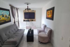ein Wohnzimmer mit einem Sofa, Stühlen und einem TV in der Unterkunft Hermoso apartamento, con todas las comodidades. in Medellín