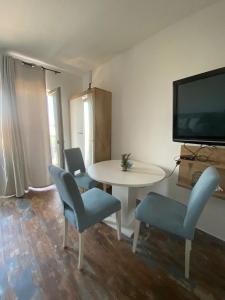 een woonkamer met een tafel en stoelen en een televisie bij Apartment Ella in Zadar