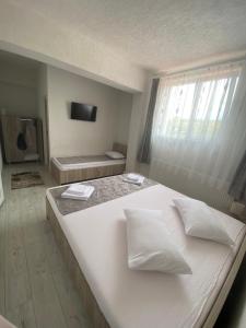 a large white bed in a room with a window at Pensiunea La Doinel in Densuş