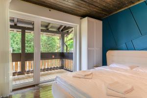 a bedroom with a large bed and a balcony at Blend Mountain Villa in Buşteni
