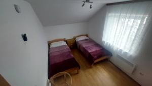two beds in a small room with a window at Apartma ASJA in Brežice