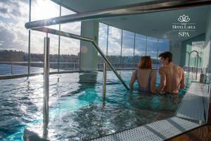 Ein Mann und eine Frau sitzen in einem Whirlpool auf einem Gebäude in der Unterkunft Gran Hotel Lakua in Vitoria-Gasteiz