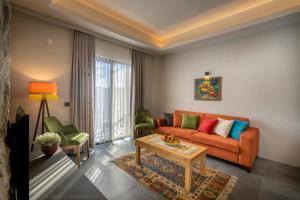 ein Wohnzimmer mit einem orangenen Sofa und 2 grünen Stühlen in der Unterkunft DADYA BORA HOTEL in Emecik