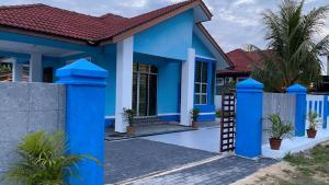 una casa azul con techo rojo en Seri Idaman Guest House (Pasir Mas) en Kampong Taman