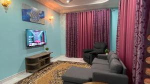 Seri Idaman Guest House (Pasir Mas) في Kampong Taman: غرفة معيشة مع أريكة وتلفزيون