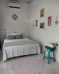 um quarto branco com uma cama e um banco azul em Buddha Suítes em Pipa