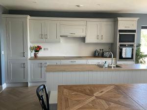 uma cozinha com armários brancos e uma mesa de madeira em Garryvoe - Ballycotton Bay & Island View em Garryvoe