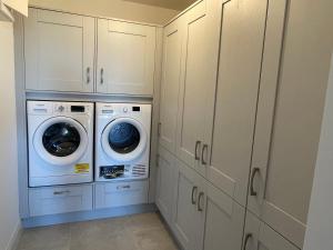 a laundry room with white cabinets and a washer and dryer at Garryvoe - Ballycotton Bay & Island View in Garryvoe