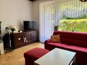 a living room with a red couch and a tv at Ferienhaus Seeröschen - Gesamte Unterkunft in Pörtschach am Wörthersee