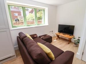 a living room with a brown couch and a flat screen tv at The Office in Witney