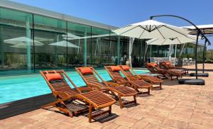 - une rangée de chaises et un parasol à côté de la piscine dans l'établissement Corte Fratini Appartamenti, à Trevi