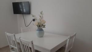 une table blanche avec un vase et des fleurs sur elle dans l'établissement Casa Lea, à Roseto degli Abruzzi