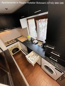 a kitchen with black and white appliances and wooden floors at Apartament frumos cu 3 camere situat la partier in Botoşani