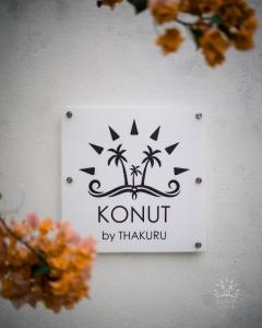 a sign on a wall with palm trees on it at Konut by Thakuru in Guraidhoo