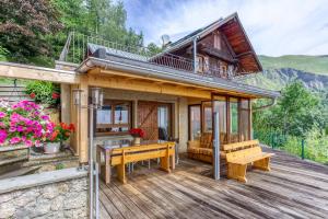 a house with a deck with a table and benches at Chalet Lo Grané in Jarrier