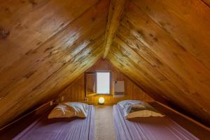two beds in a wooden attic room with a window at Chalet Lo Grané in Jarrier