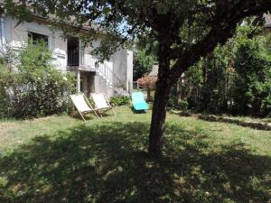 zwei Stühle in einem Garten neben einem Baum in der Unterkunft Petite maison rustique 