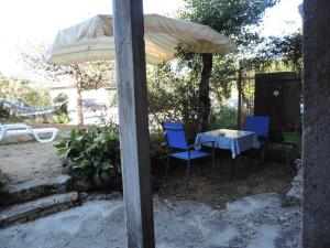 einen Tisch und Stühle unter einem Regenschirm im Hof in der Unterkunft Petite maison rustique 
