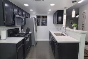 una cocina con armarios negros y encimeras blancas en L - Fully remodeled and professionally decorated en Las Vegas