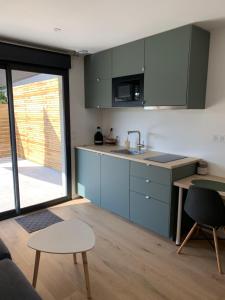 a kitchen with blue cabinets and a table at Studio La Petite Forge in Castelnau-de-Médoc