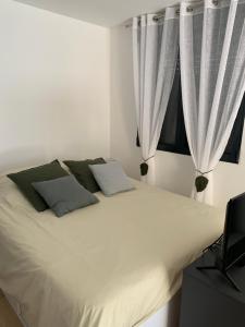 1 cama blanca con cortinas blancas y TV en Studio La Petite Forge, en Castelnau-de-Médoc