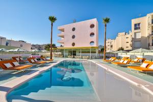 una piscina con tumbonas y un edificio en Grand Paradiso Ibiza - Adults Only, en Bahía de San Antonio