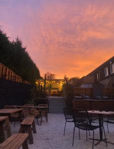 a patio with wooden tables and chairs at sunset at The Bonnie Badger in Gullane