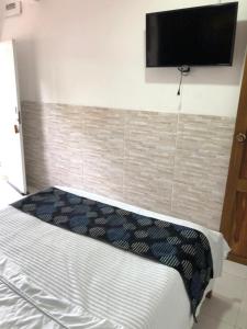 1 dormitorio con 1 cama y TV de pantalla plana en la pared en Habitacion Coveñitas 7, en Coveñas