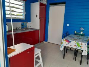 una cocina con paredes rojas y azules y una mesa. en Bougainvilliers, en Schœlcher
