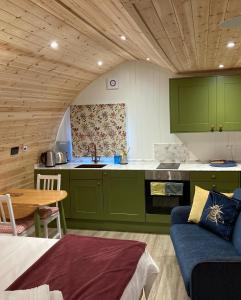 een keuken met groene kasten en een blauwe bank bij Bedrule Old Manse Glamping in Hawick