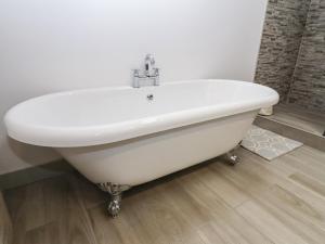 a white bath tub sitting in a bathroom at The Cow Shed at Pear Tree Farm in Doncaster