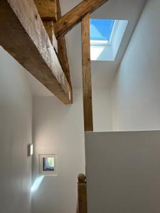 uma clarabóia num quarto com paredes brancas e vigas de madeira em Superbe maison de ville, rénovée à 15 min de Lyon em Saint-Symphorien-dʼOzon
