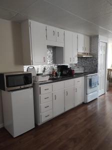 a kitchen with white cabinets and white appliances at Private Home in downtown Edmundston! in Edmundston