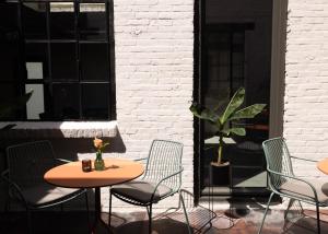 een patio met 2 tafels en stoelen en een plant bij Cousins Boutique Hotel in Maastricht