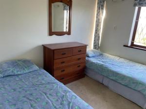 a bedroom with two beds and a dresser and a mirror at Wild coast Sea view House in Port Edward