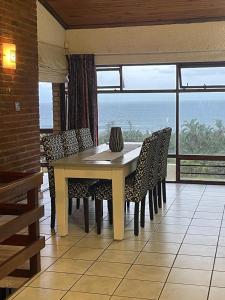 a table and chairs in a room with a view of the ocean at Wild coast Sea view House in Port Edward